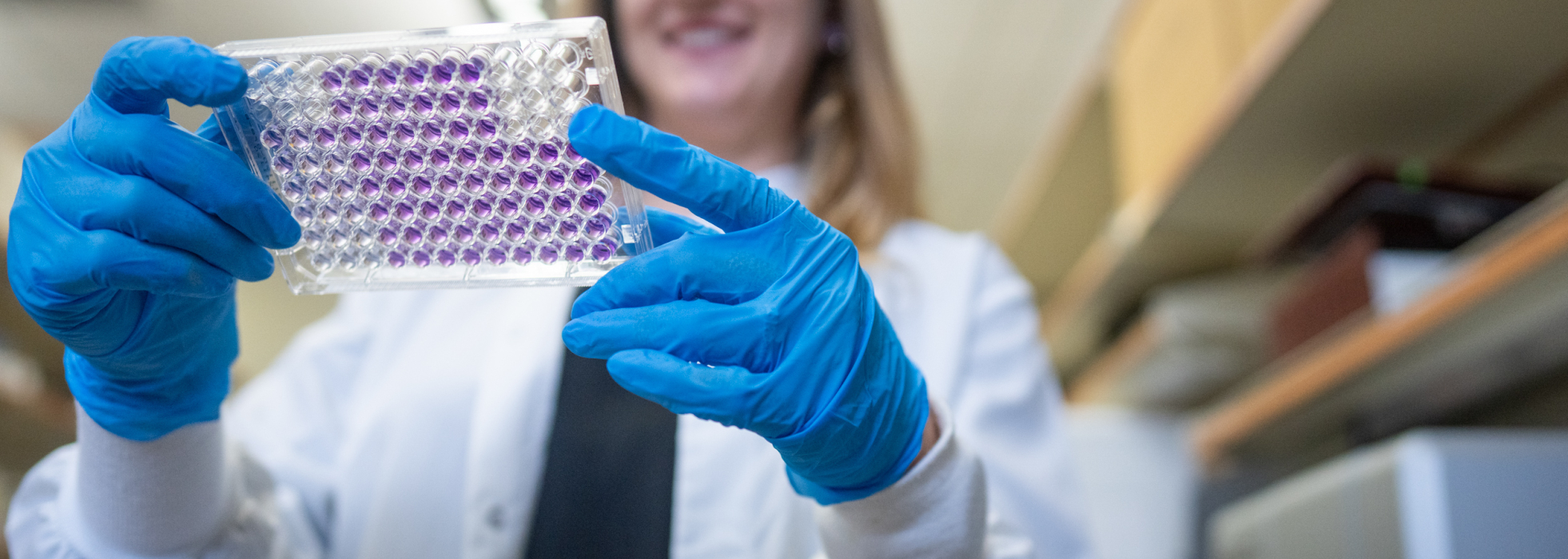 Photo of female scientist in white coat holding tray of specimens
