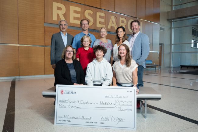 Photo of some of the Dotzauer family and friends, with Heather Dotzauer at lower right, gathered for a check presentation with Dr. Hector Valdivia, at top left, representing the Division of Cardiovascular Medicine.