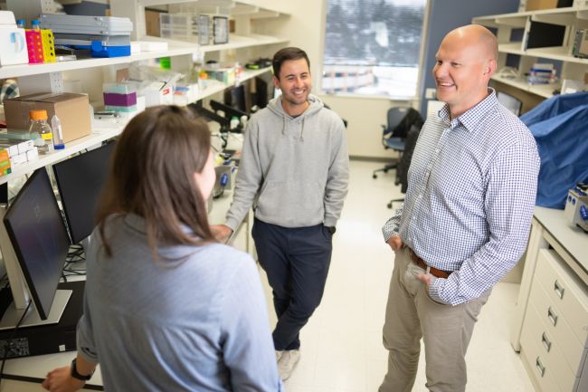 Dr. Sundberg talks with two research team members in his lab at the Wisconsin Institutes for Medical Research.