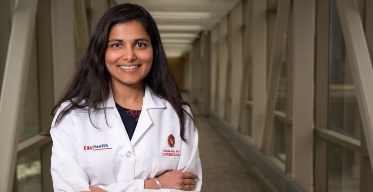 Dr. Shivani Garg in her white coat, standing in a hallway.