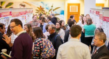Participants mingle at the 2026 DOM Education Day poster presentation.