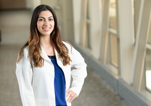 Dr. Rita German wearing a white coat, standing by windows in the pedestrian bridge by UW Health University Hospital