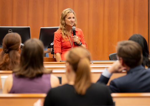 Laura Maursetters speaks into a microphone in front of a lecture hall of people