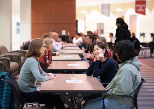 A room of people sitting across from each other at tables in a row